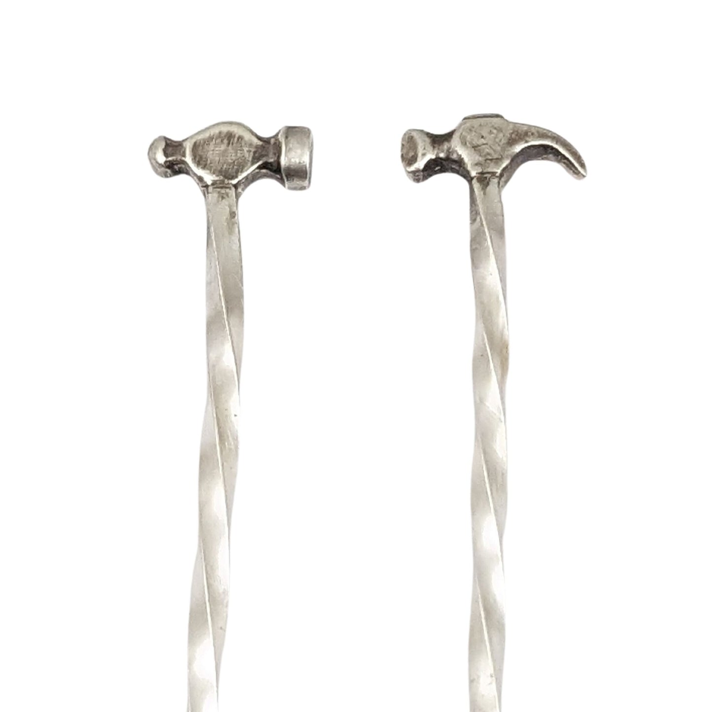 Sterling silver cocktail pick. One pick has a small ball peen hammer at the top, the other has a small claw hammer. Wire portion of the pick is twisted.