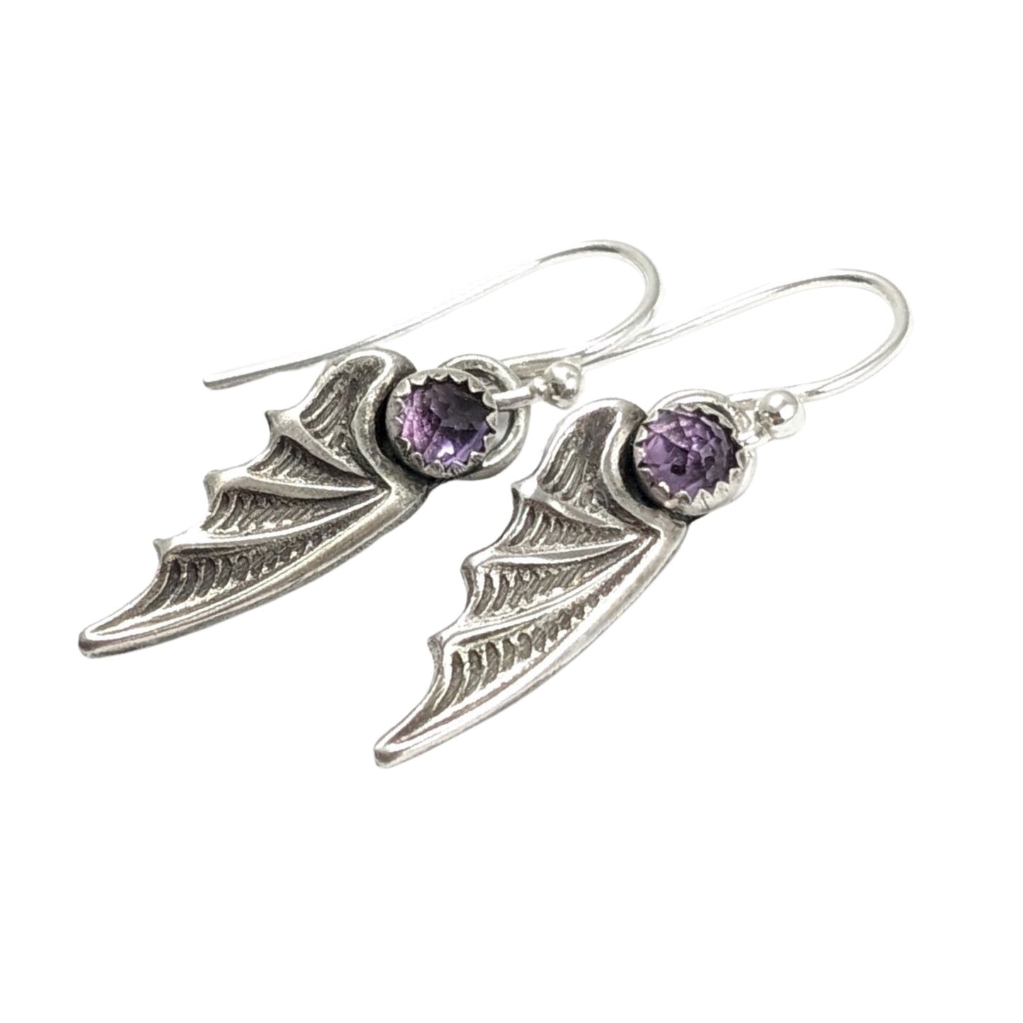 Bat wing shaped earrings with a rose cut light purple amethyst gemstone on top. On silver ear wires.