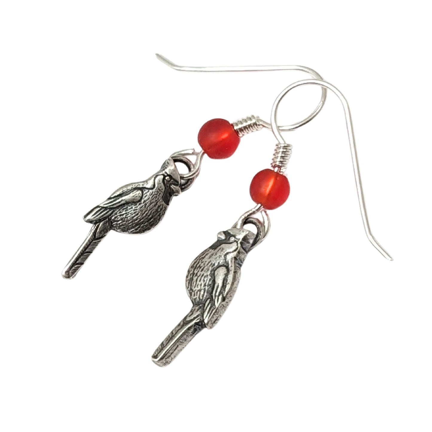 Cardinal birds as sterling silver earrings. There is one left facing Cardinal and one right facing cardinal. Above the Cardinals, attached to the ear wire, is a red Czech glass bead.