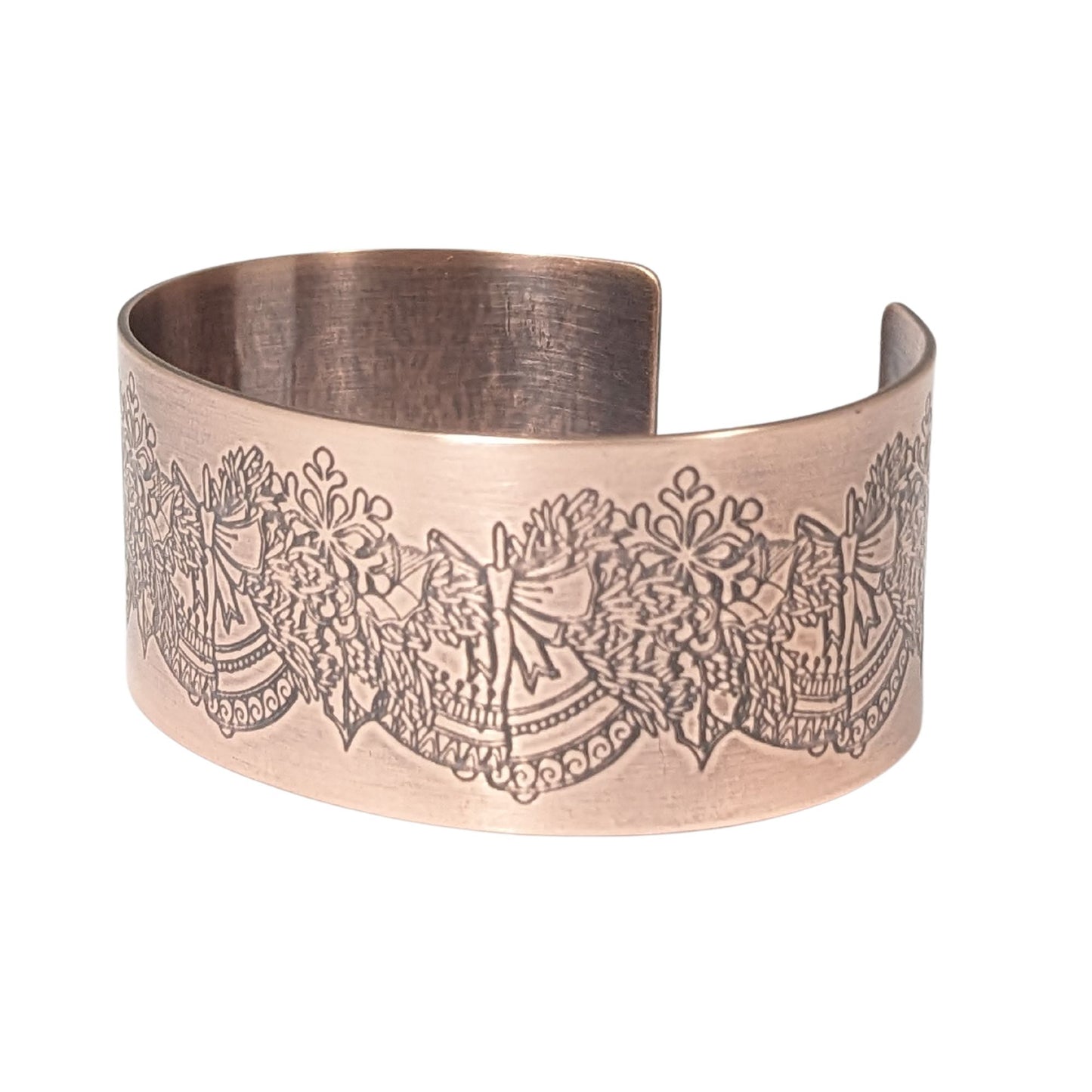 copper cuff bracelet. pattern along entire length is an evergreen bough with pairs of bells.