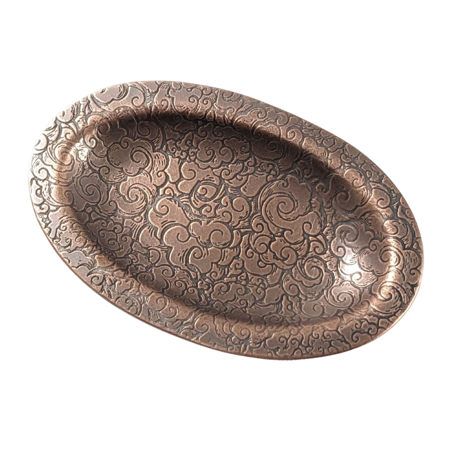 An oval copper ring dish with a raised edge. The dish has an impressed pattern of clouds.