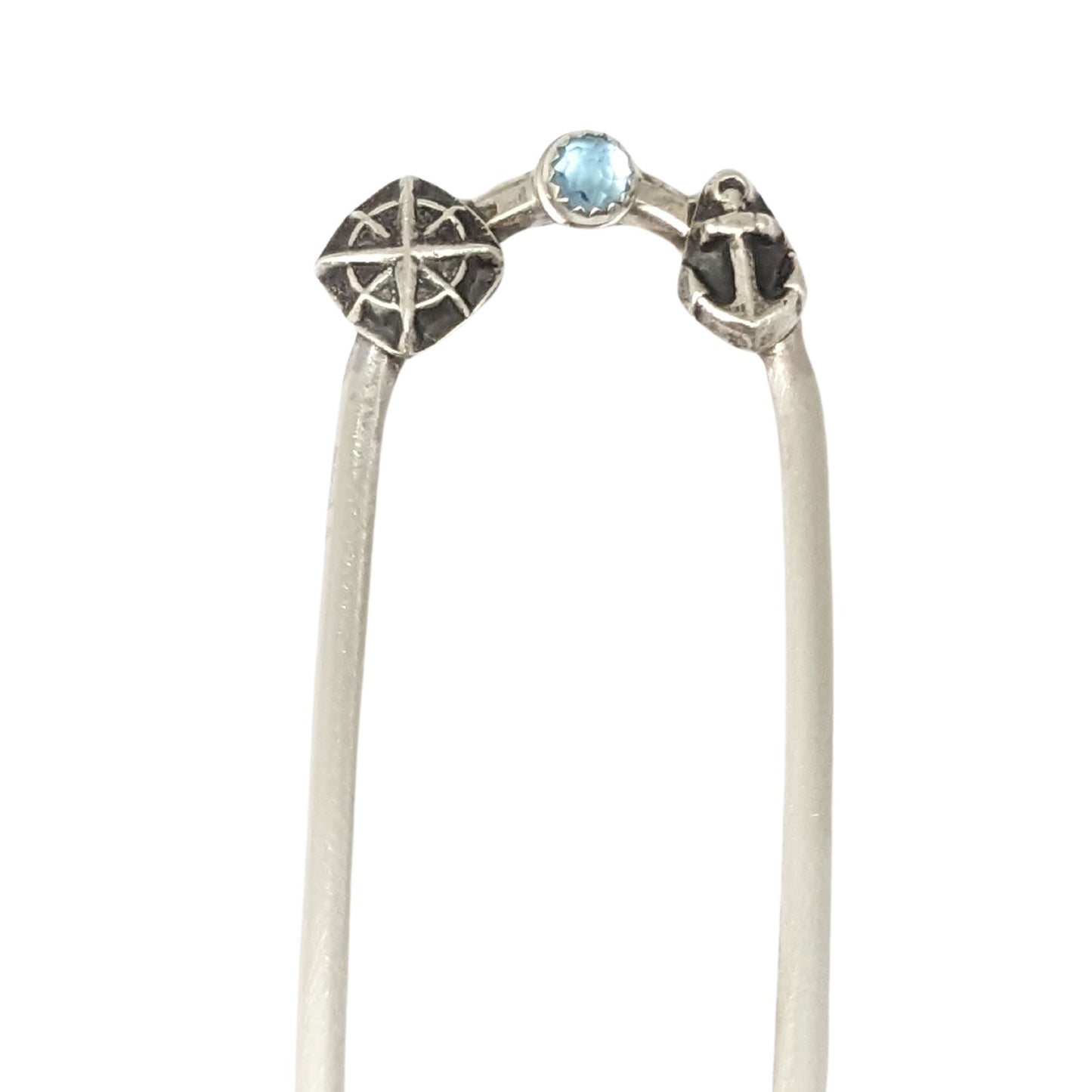 Sterling silver hair fork with three small design elements. Left is a silver compass rose, center is a rose cut blue topaz gemstone, right is a silver anchor