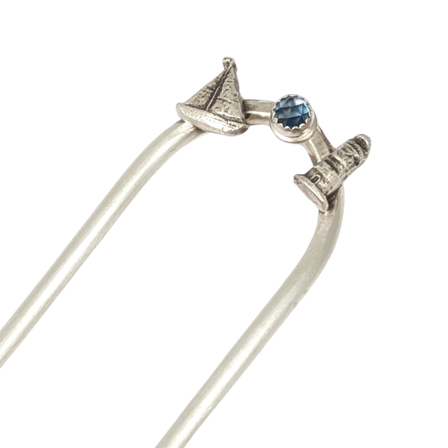 Sterling silver hair fork with three small design elements. Left is a silver sailboat, center is a rose cut blue topaz gemstone, right is a silver lighthouse
