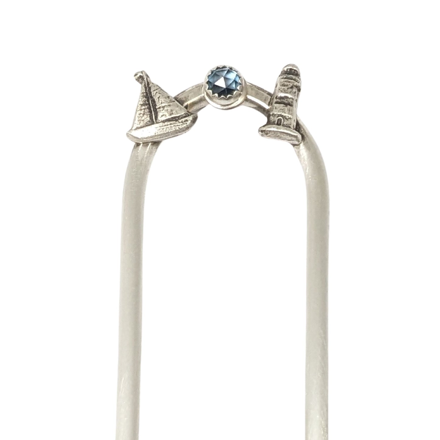 Sterling silver hair fork with three small design elements. Left is a silver sailboat, center is a rose cut blue topaz gemstone, right is a silver lighthouse