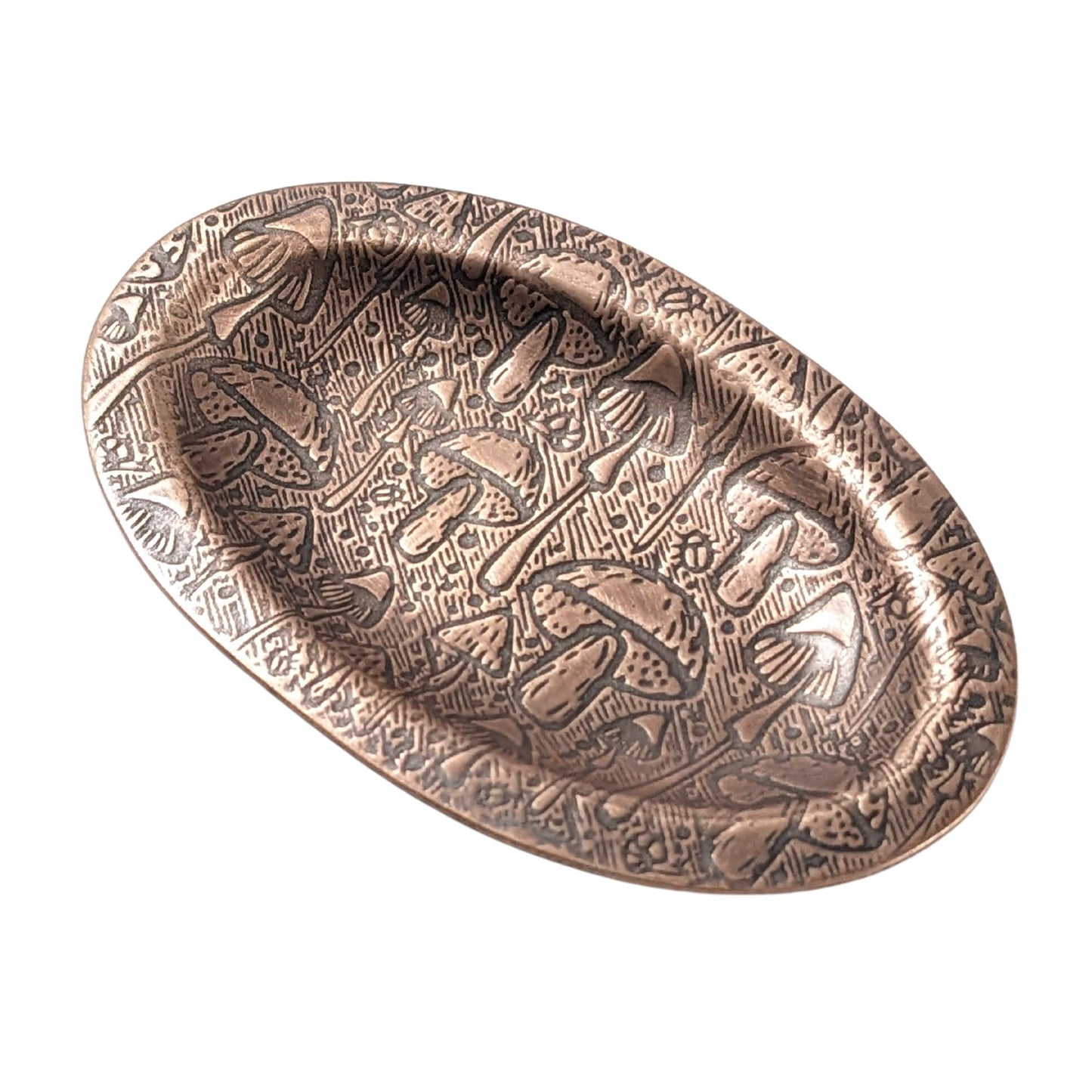 An oval copper ring dish with a raised edge. The dish has an impressed pattern of a variety of mushrooms