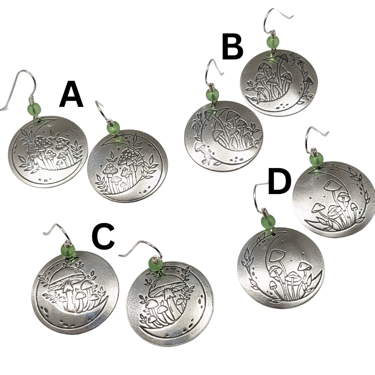 Four pair of domed sterling silver round drop earrings featuring an engraved mushroom and crescent moon design, accented with small green beads and silver ear wires. The designs are labeled A, B, C, and D.