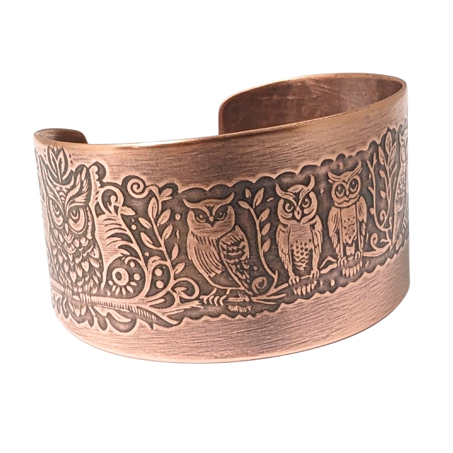 Wide tapered copper cuff bracelet. A design of various owls on a tree branch wraps the entire length of the bracelet.