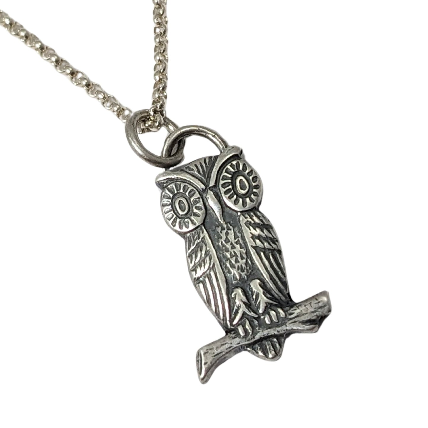 Sterling silver pendant of an owl sitting on a branch. The owl has large cartoonish eyes.