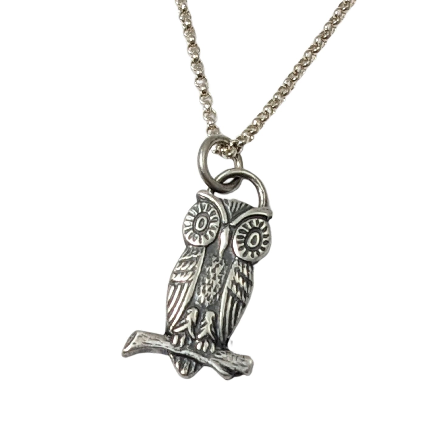 Sterling silver pendant of an owl sitting on a branch. The owl has large cartoonish eyes.