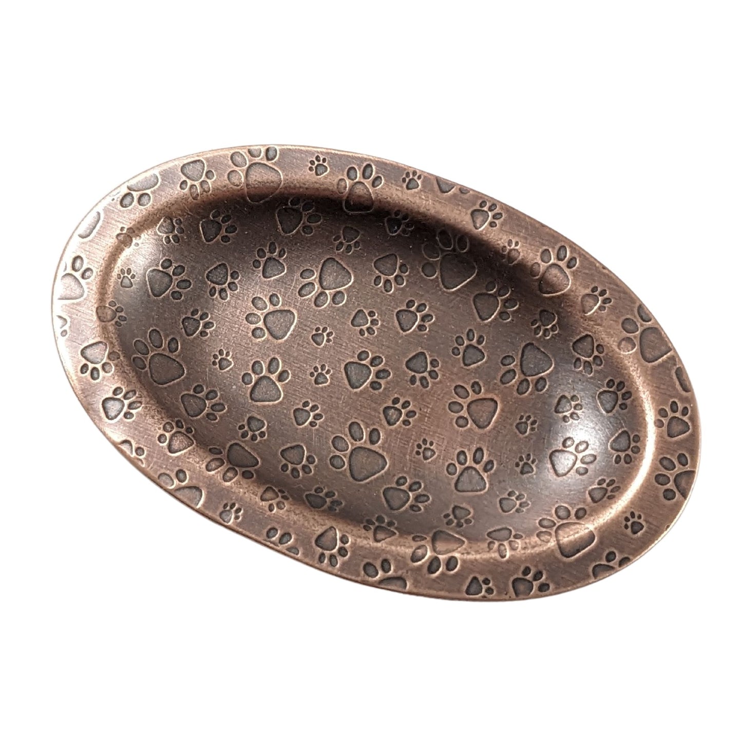 An oval copper ring dish with a raised edge. The dish has an impressed pattern of dog paw prints.