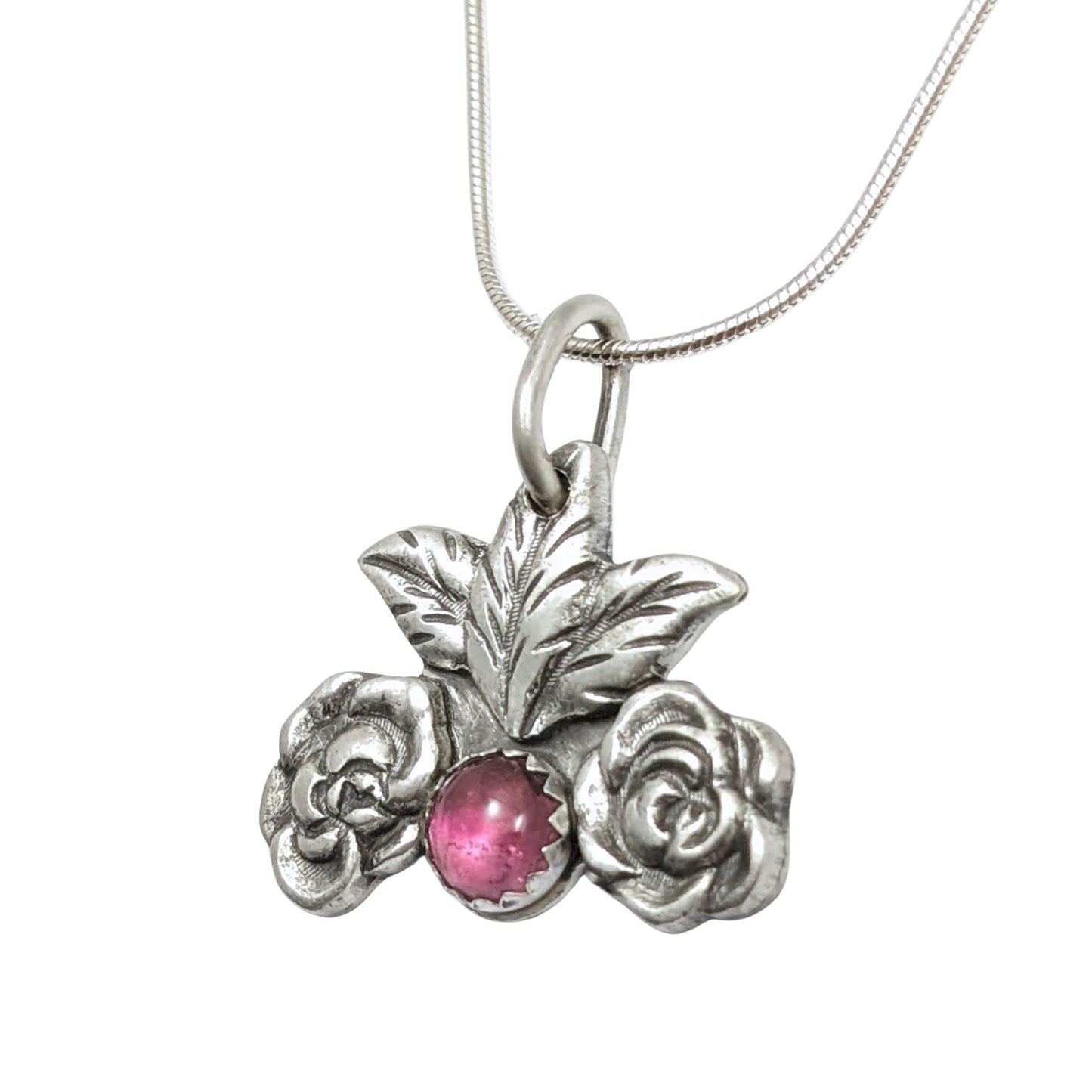 Silver pendant on a chain. At the bottom center there is a large pink tourmaline gemstone. There's a silver rose on each side of the gemstone and two leaves above it.