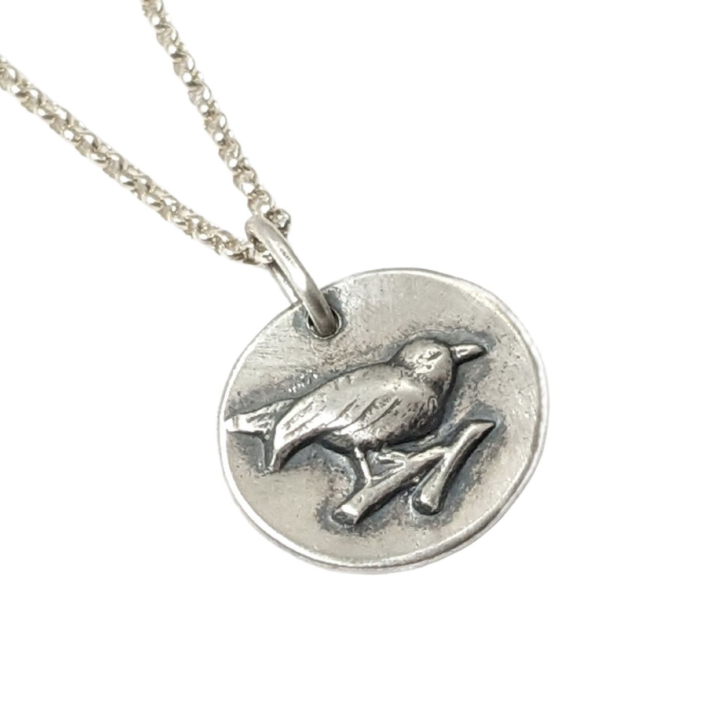 Small round sterling silver pendant with a songbird perched on a branch.