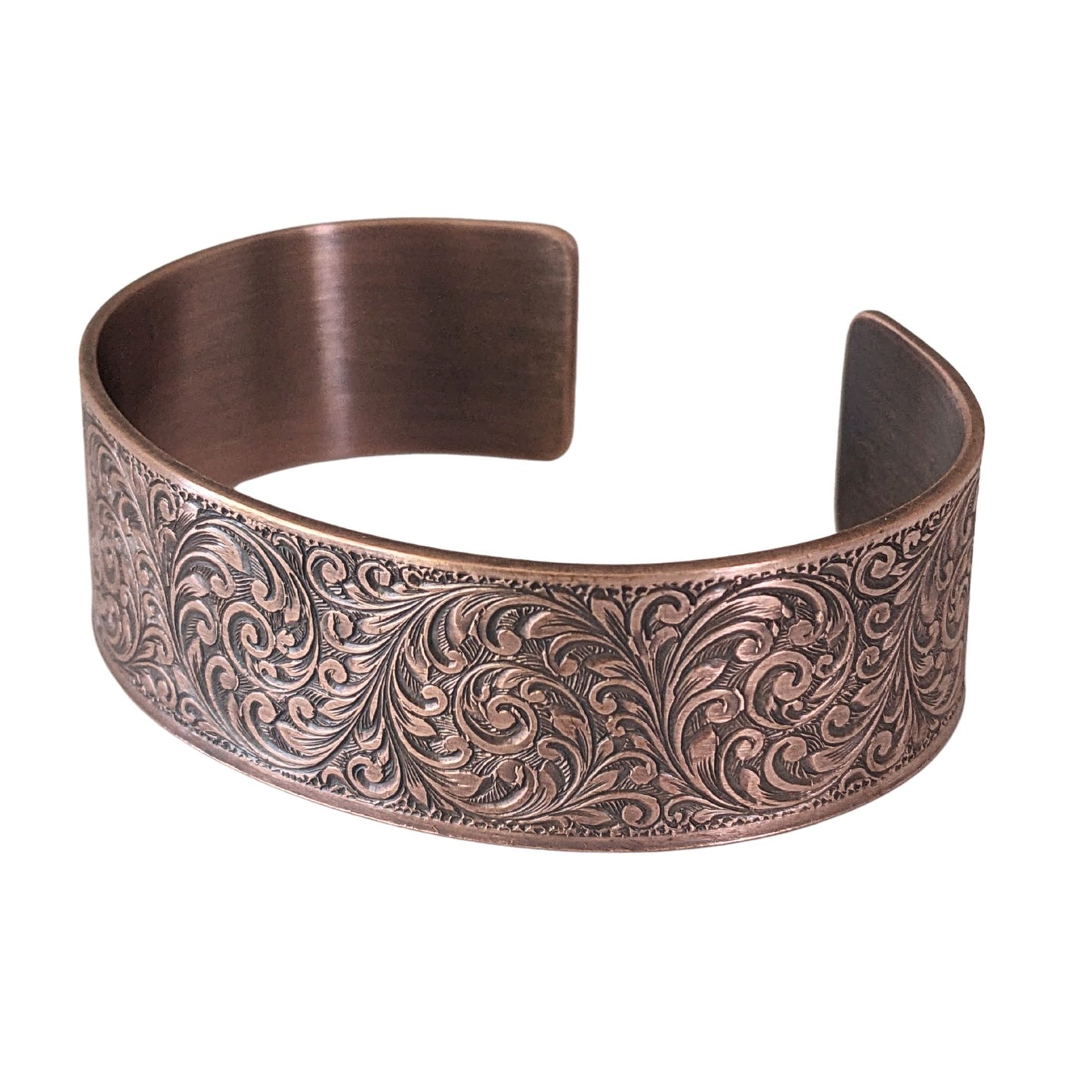 copper cuff bracelet with a detailed design of flourishes in a repeated spiral pattern