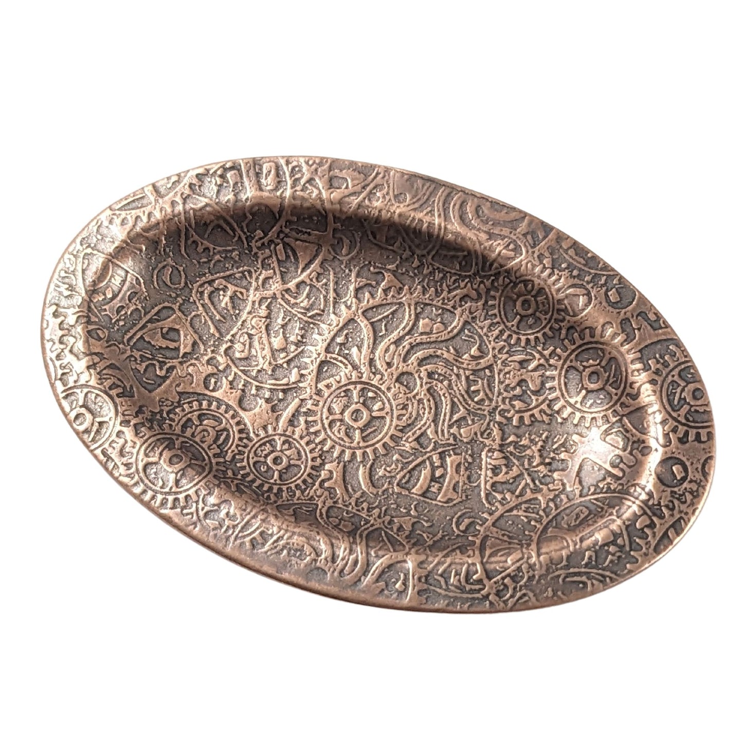 An oval copper ring dish with a raised edge. The dish has an impressed pattern of steampunk style gears and cogs.