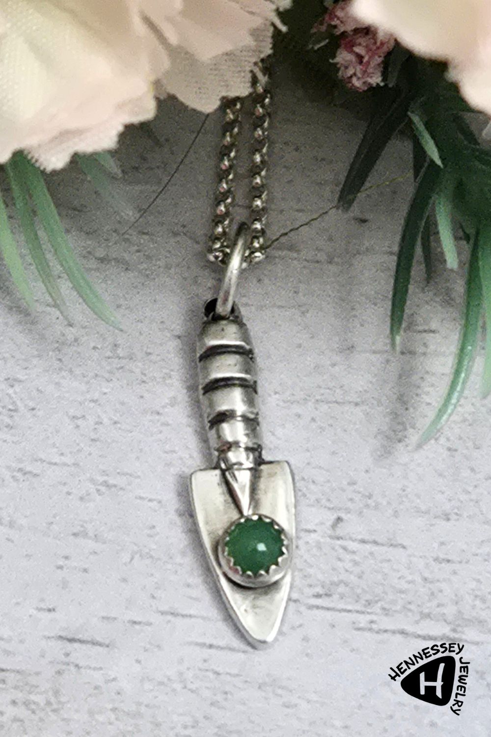Three dimensional sterling silver garden hand trowel pendant with a faceted green chrysoprase gemstone on the trowel handle.