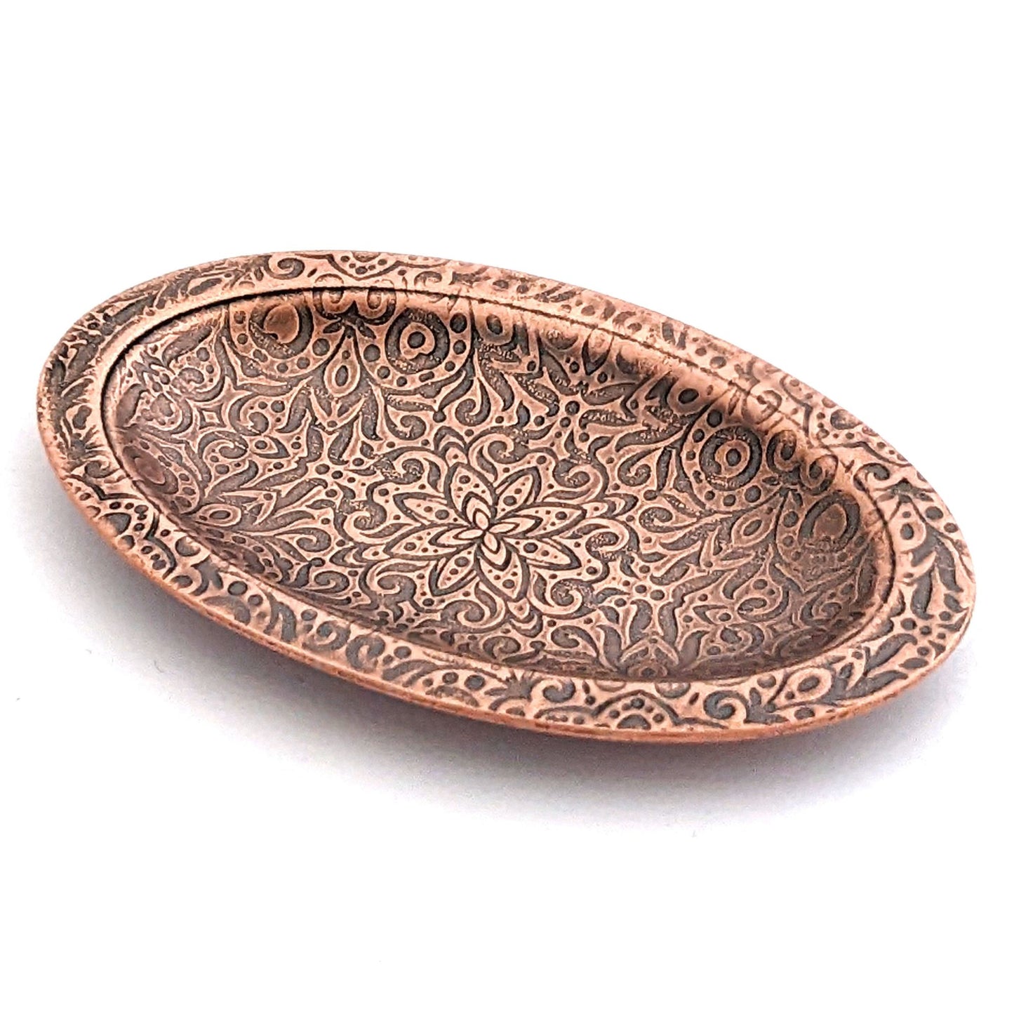 Copper oval ring dish with abstract garden flowers and leaves design. Dish is 2 inches by three inches with a raised lip.