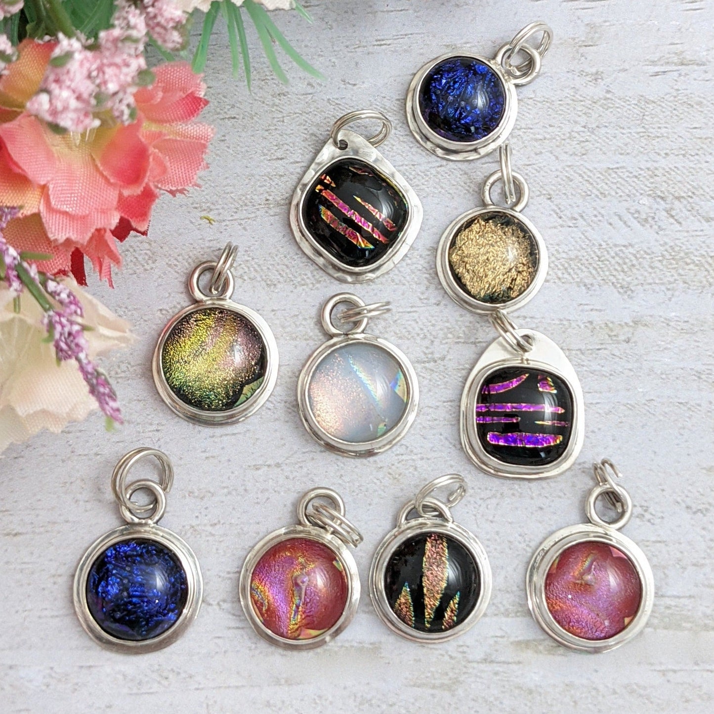 Jewelry charms. Dichroic glass round and square shapes in different colors set in sterling silver with split rings added to hang from bracelet or necklace