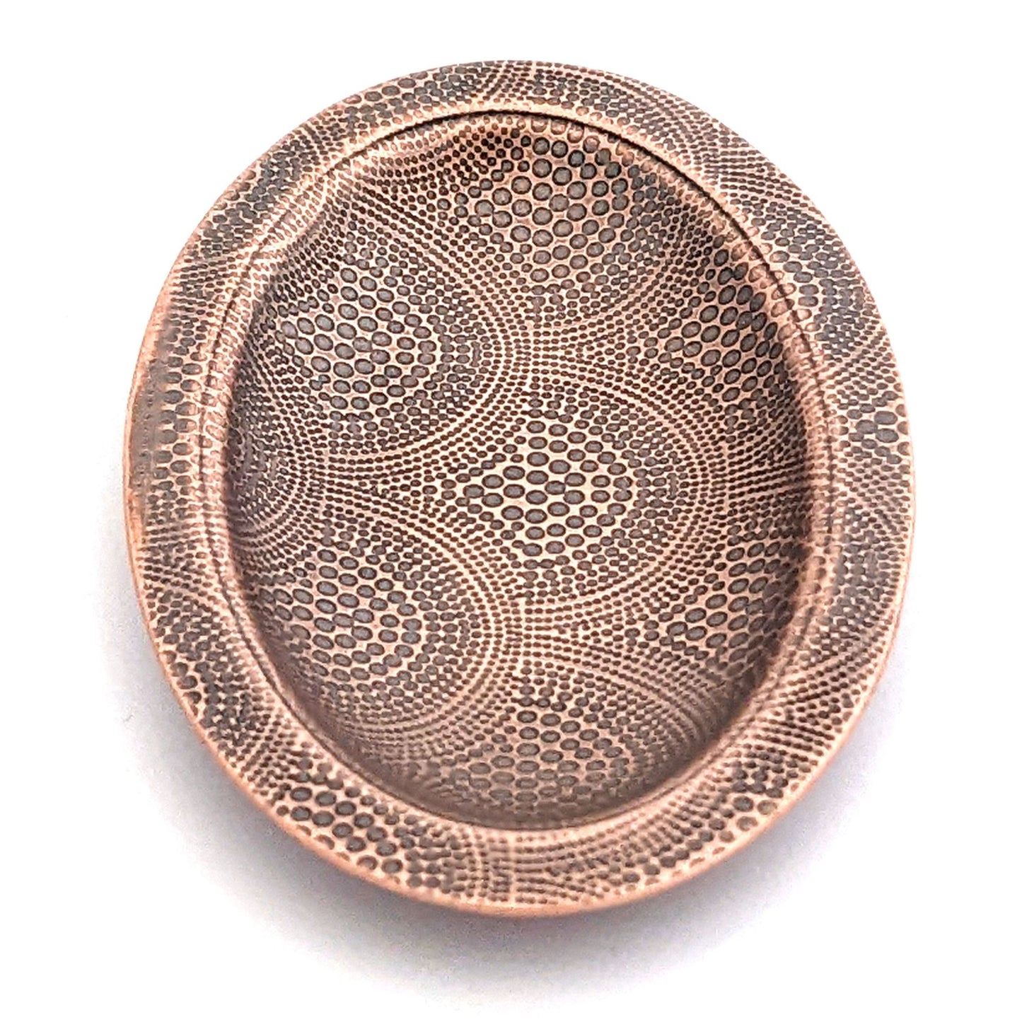 Copper oval ring dish with repeating pattern of dotted arches. Dish is 2 inches by three inches with a raised lip.