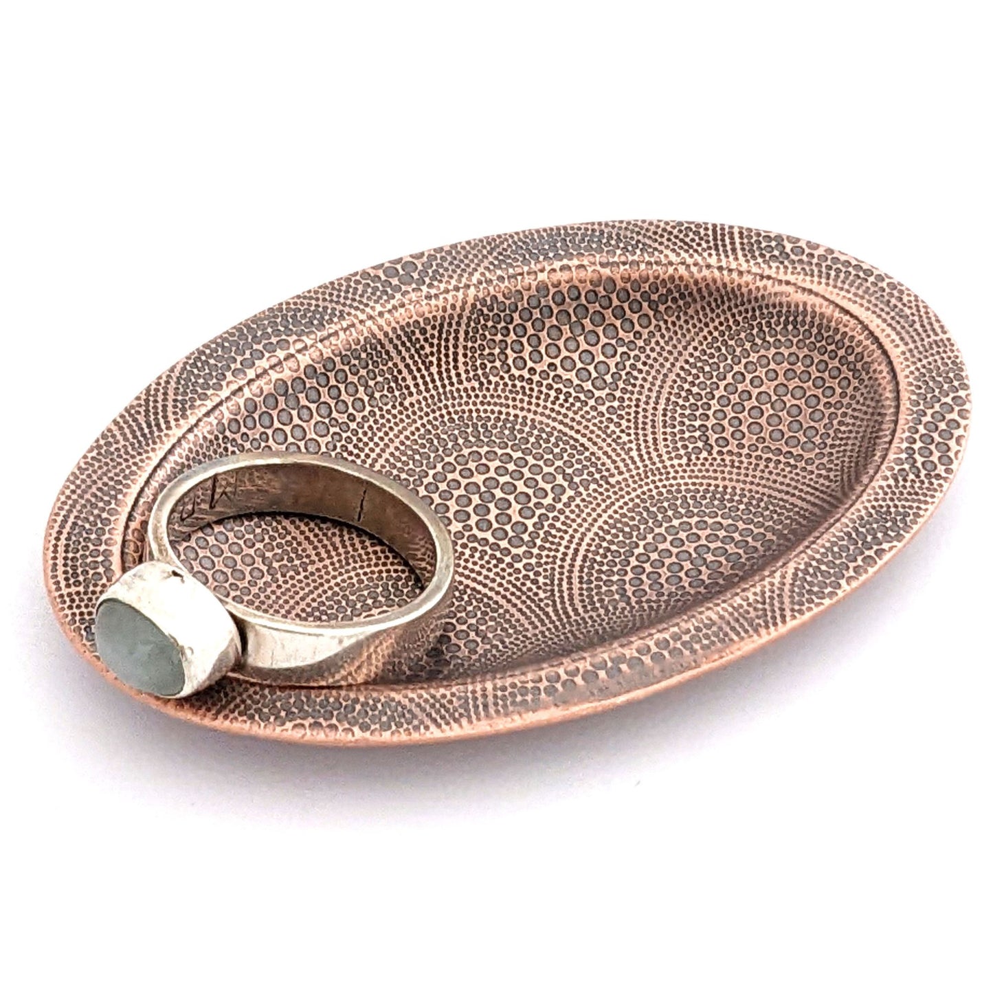 Copper oval ring dish with repeating pattern of dotted arches. Dish is 2 inches by three inches with a raised lip.