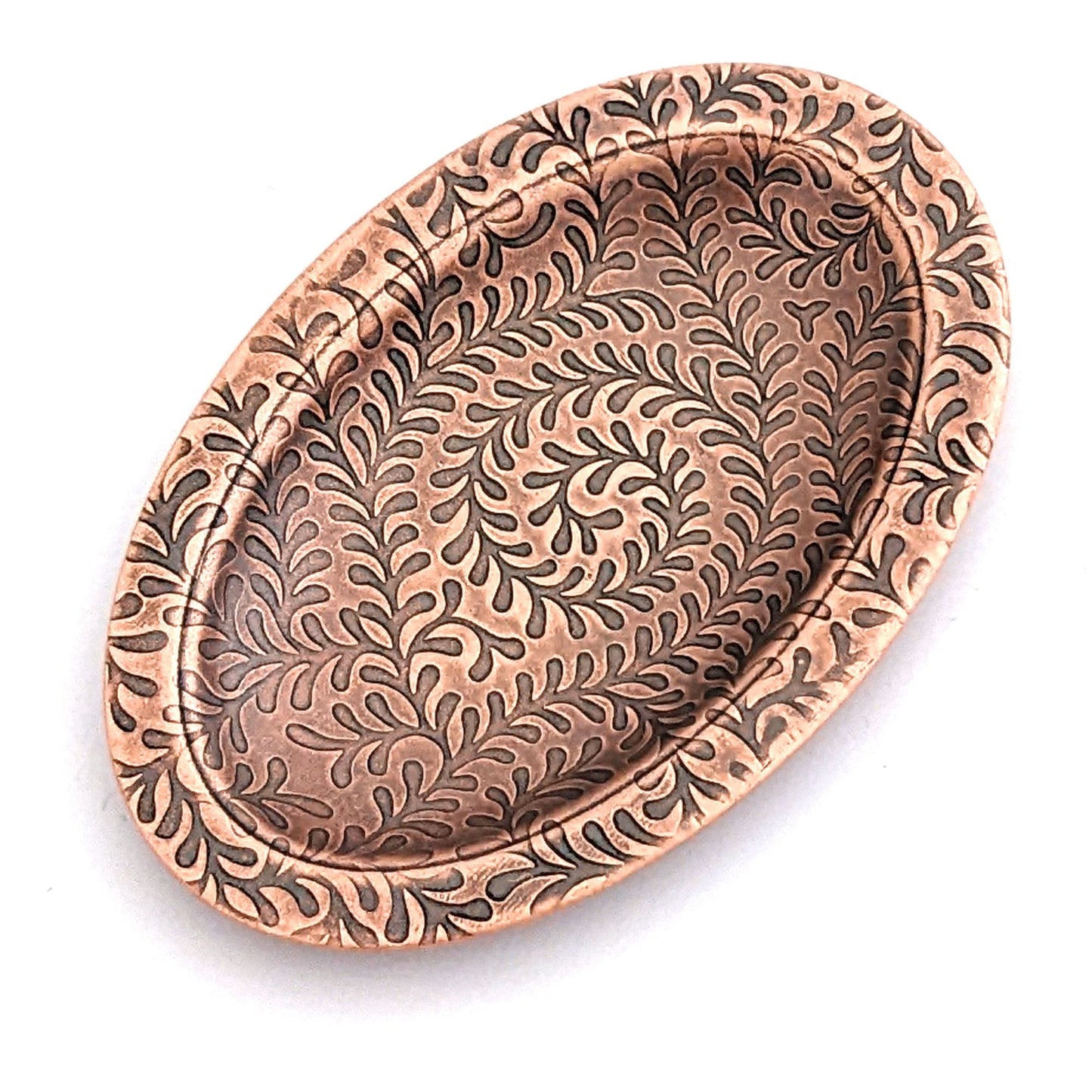 Copper oval ring dish with abstract fiddlehead fern pattern. Dish is 2 inches by three inches with a raised lip.