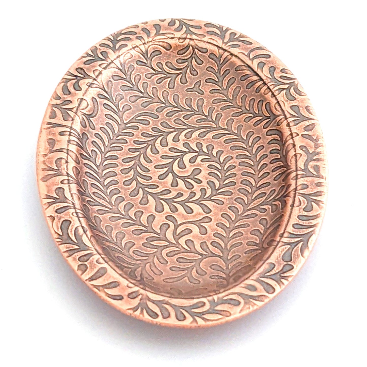 Copper oval ring dish with abstract fiddlehead fern pattern. Dish is 2 inches by three inches with a raised lip.