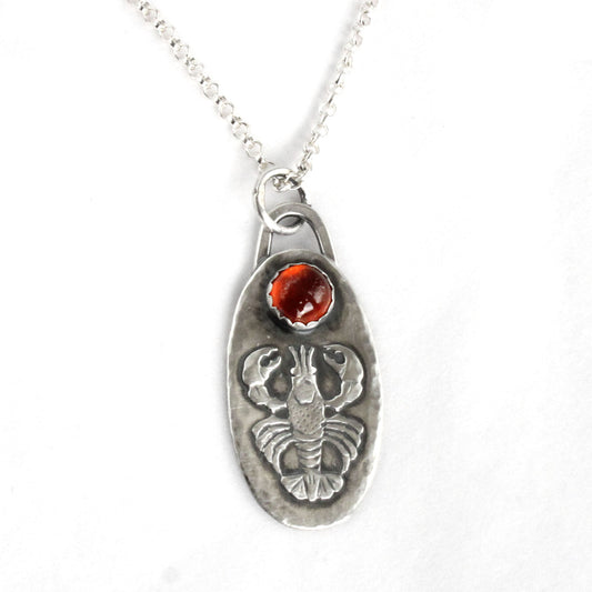 Lobster Sterling Silver Pendant with Hessonite Garnet. The pendand has a detailed raised impression of a lobster. Above the lobster is a 6mm hessonite garnet stone. The pendant is 1-1/4 inches long and about 5/8 inches wide and comes on an 18 inch sterling silver rolo chain.