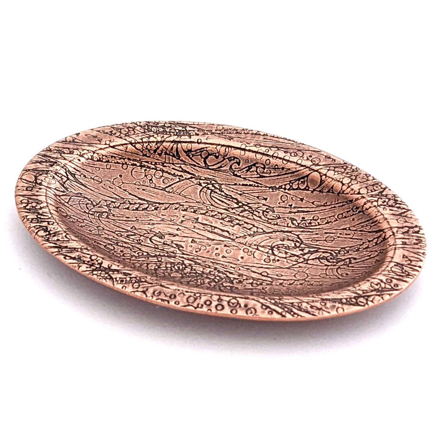Copper oval ring dish with design of waves in a stormy sea. Dish is 2 inches by three inches with a raised lip.