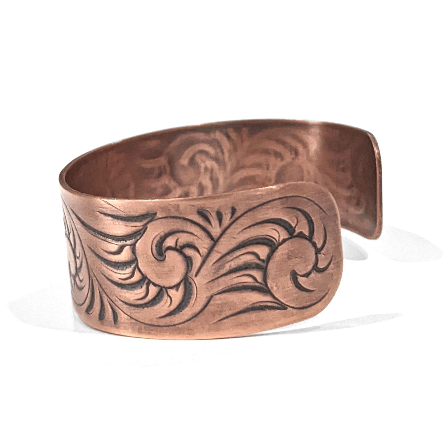Copper cuff bracelet with a sunflower in the middle , surrounded by abstract flourish swirls. Side view showing the flourish design.