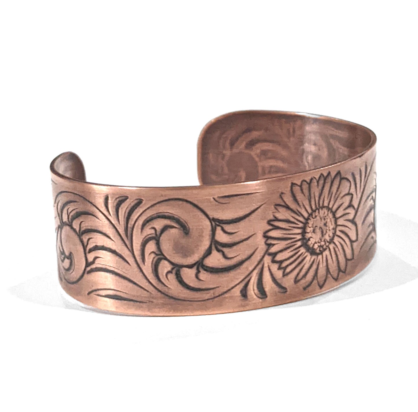 Copper cuff bracelet with a sunflower in the middle , surrounded by abstract flourish swirls. Side view showing the flourish design.