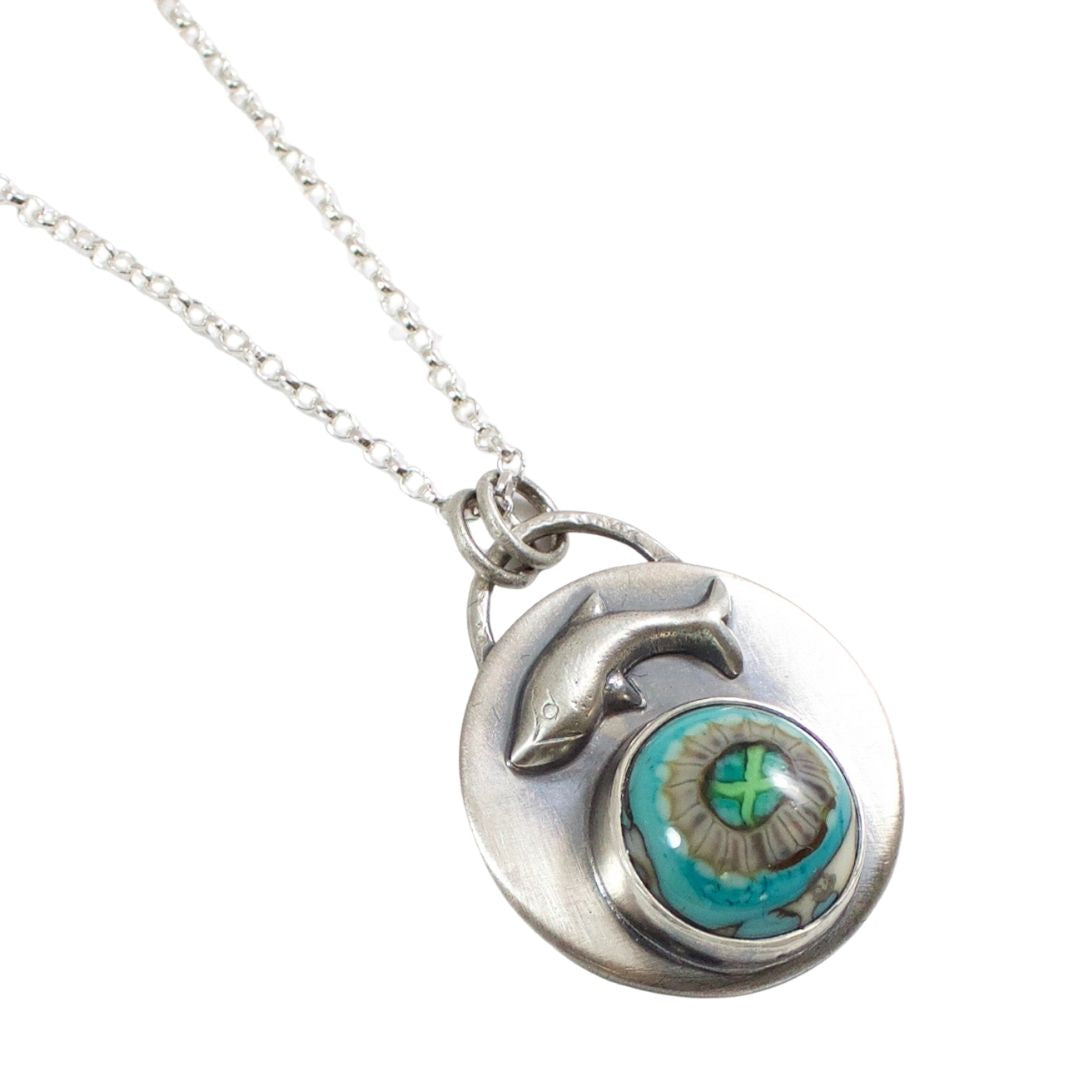 Handmade sterling silver pendant with a gray and aqua stone that looks like a sea anemone. Above the stone is a raised breaching whale design.