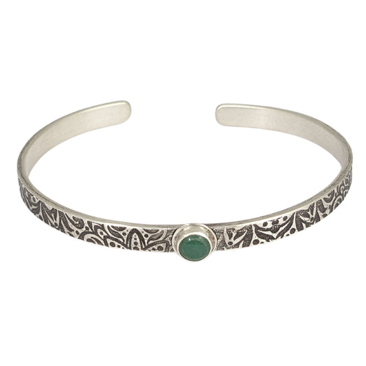 Narrow sterling silver cuff bracelet with a green aventurine gemstone. The rectangular silver wire has a n abstract impressed design, and the impression is oxidized black to bring out the details.