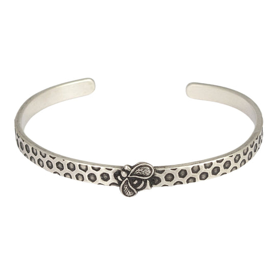 Narrow sterling silver cuff bracelet with a hexagon honeycomb pattern. A the center of the cuff there's a sterling silver honeybee.
