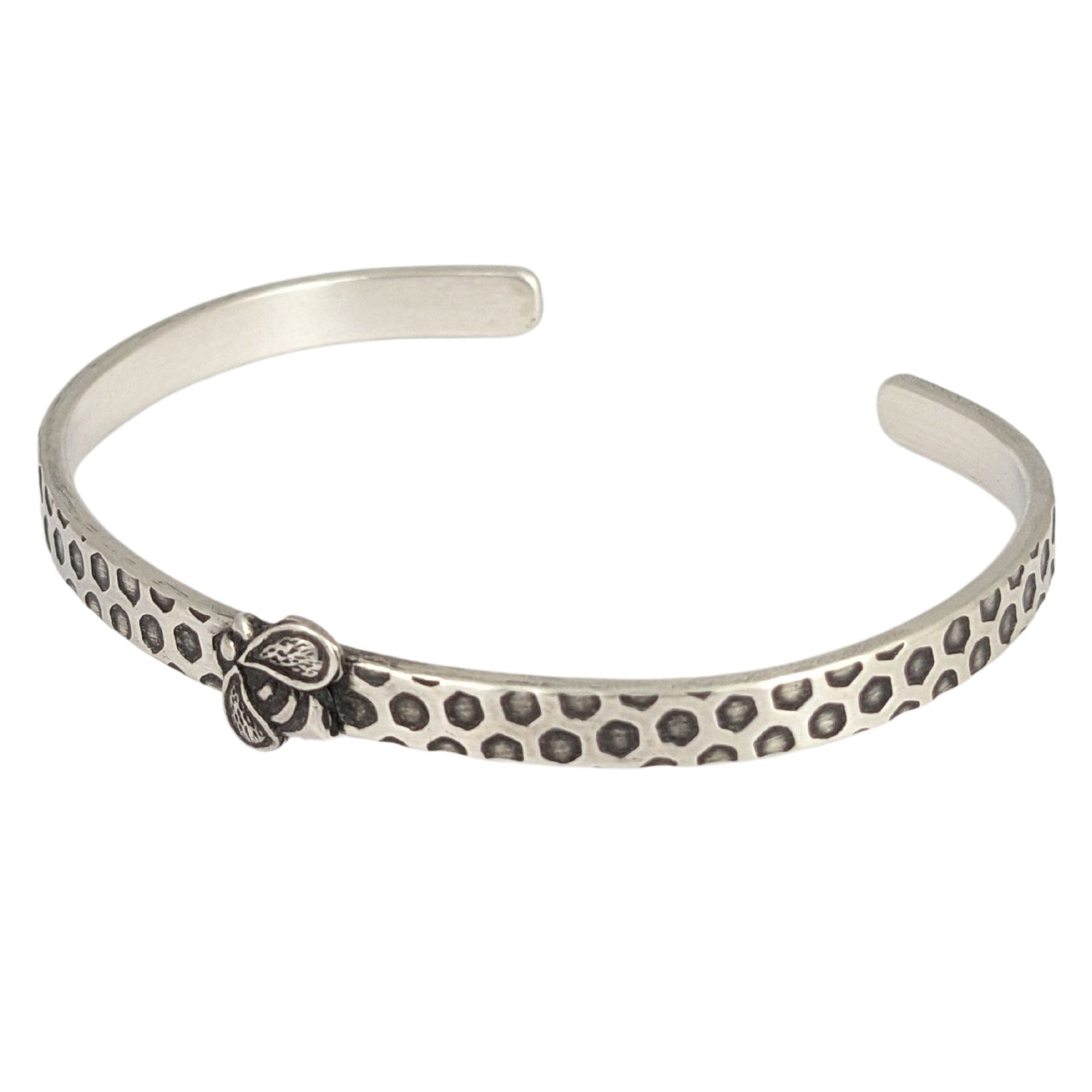 Narrow sterling silver cuff bracelet with a hexagon honeycomb pattern. A the center of the cuff there's a sterling silver honeybee.