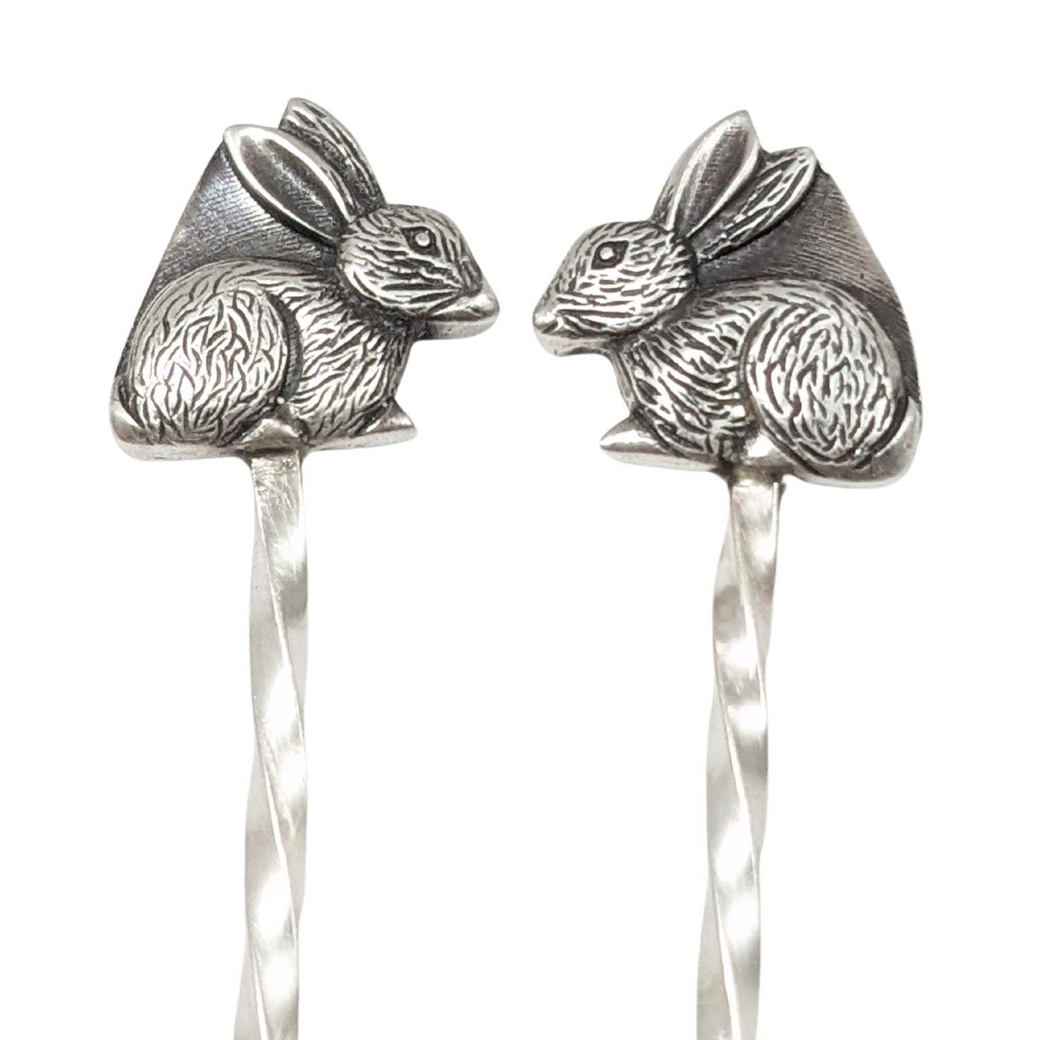Sterling silver cocktail picks with silver rabbits on top. One rabbit faces left, the other faces right.