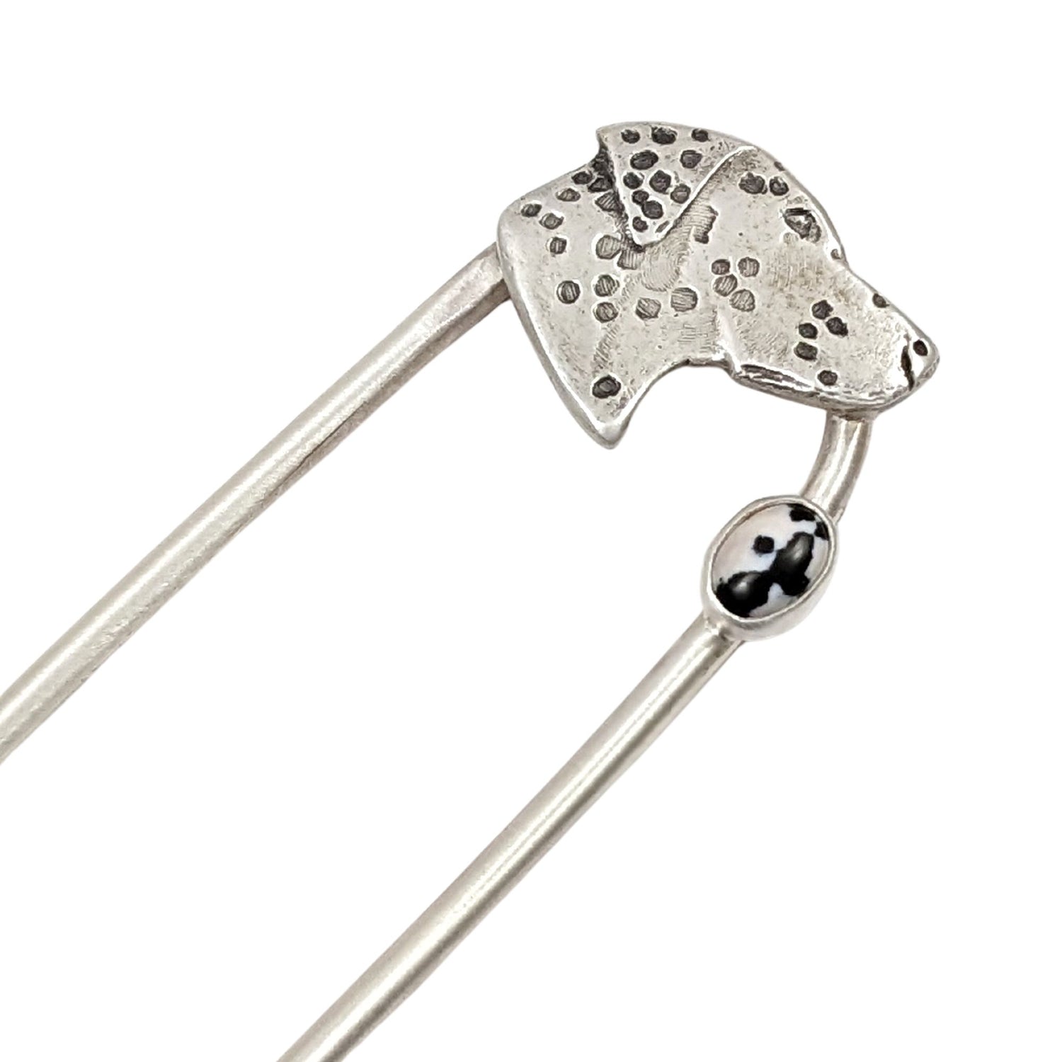 Sterling silver hair fork. Design is a profile of a dalmatian dog head and neck. There is a small oval black and white stone near the top of the right fork. The dalmatian spots are darkened.
