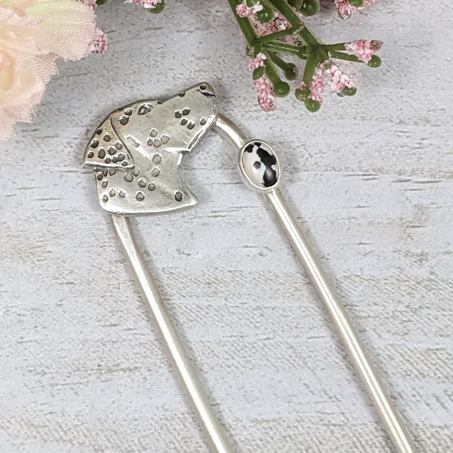 Sterling silver hair fork. Design is a profile of a dalmatian dog head and neck. There is a small oval black and white stone near the top of the right fork. The dalmatian spots are darkened.