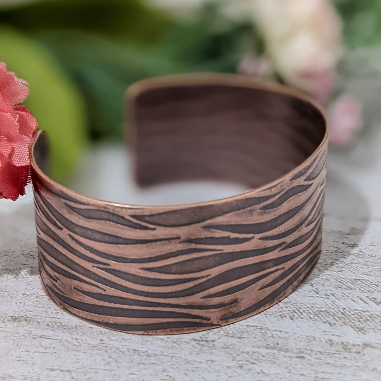 copper cuff bracelet with impressed design that looks like gently rippling water surface