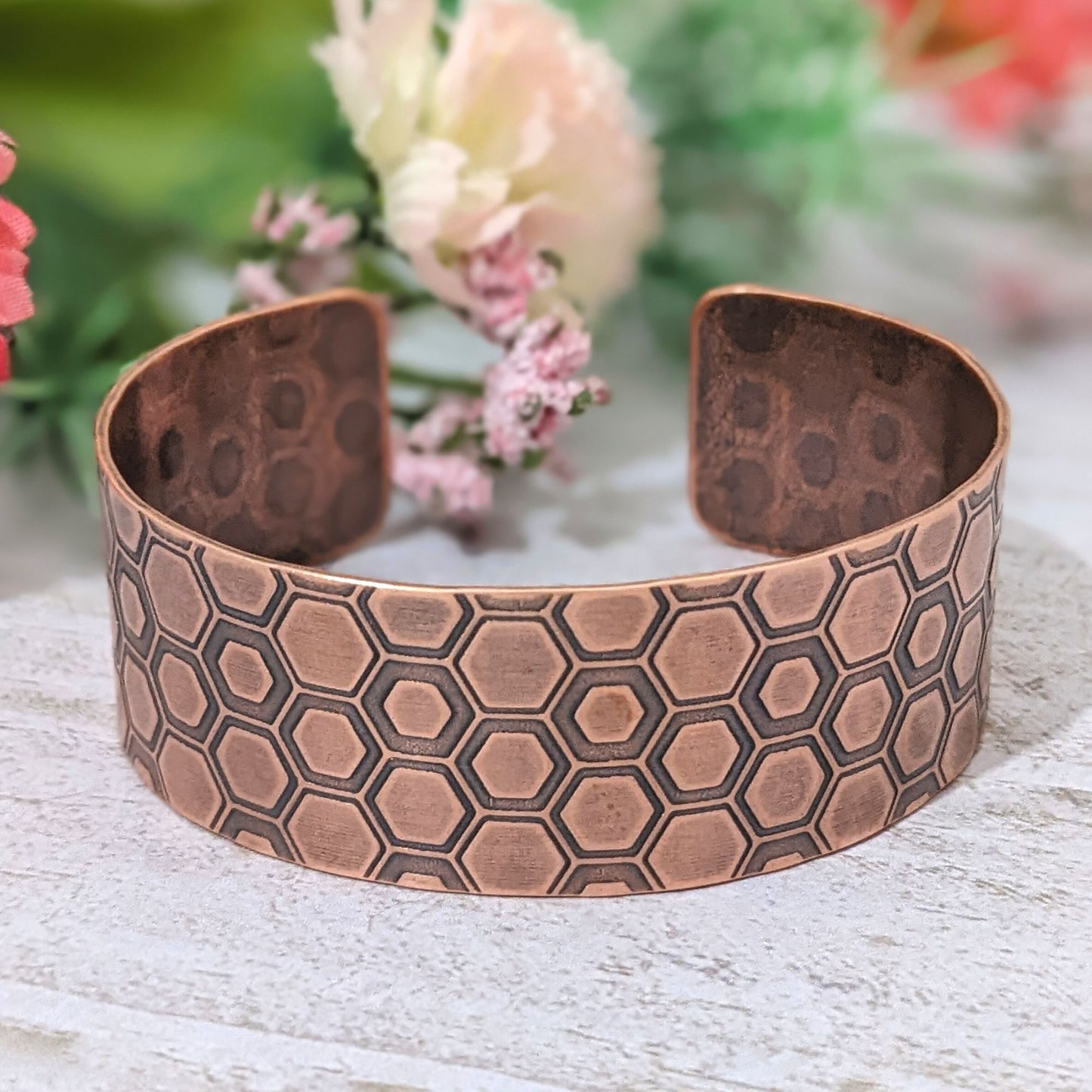 One inch wide copper cuff bracelet with a honeycomb pattern. Each vertical row of combs has a little over 3  combs. The comb edges are impressed into the copper and darkened to bring out the detail.