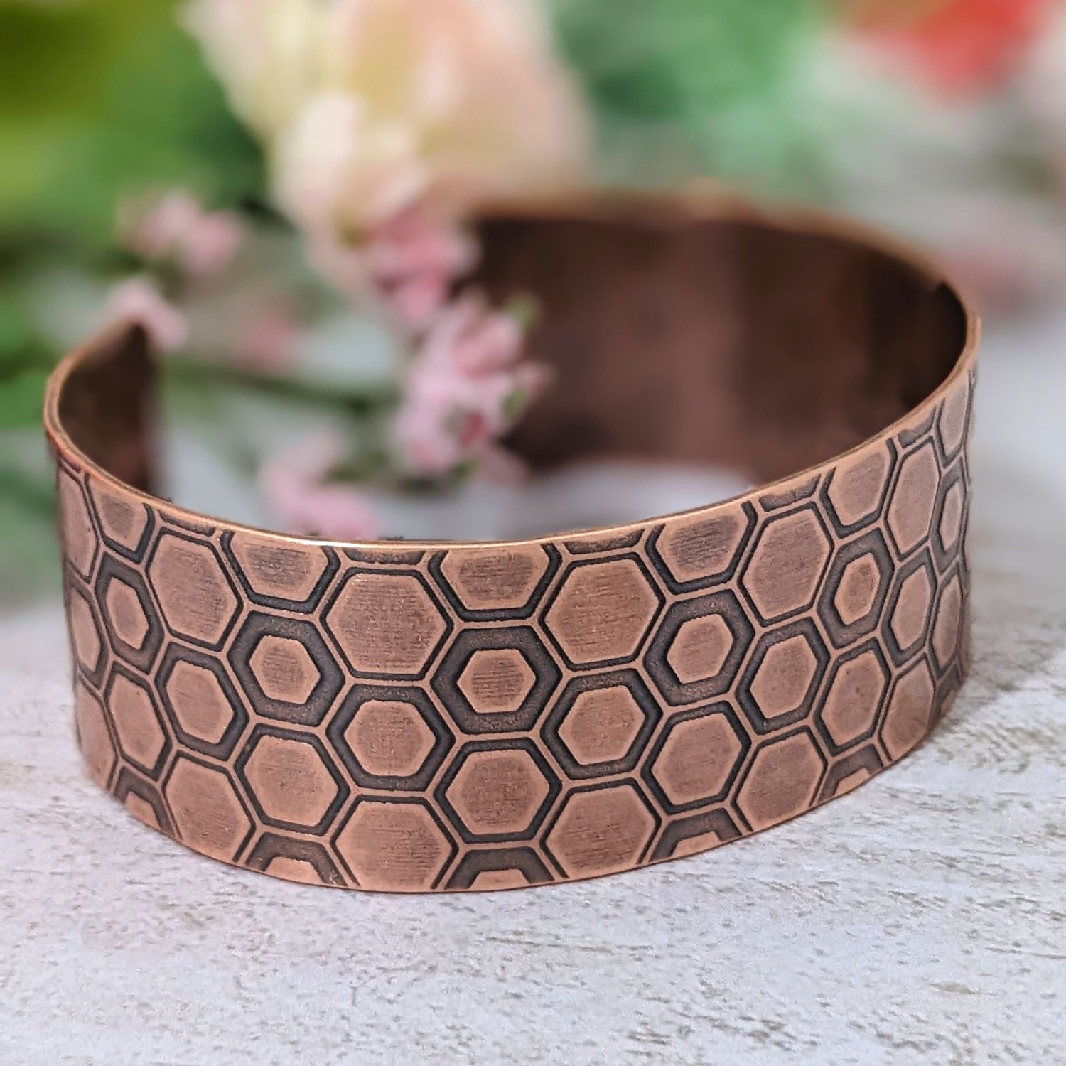 One inch wide copper cuff bracelet with a honeycomb pattern. Each vertical row of combs has a little over 3  combs. The comb edges are impressed into the copper and darkened to bring out the detail.