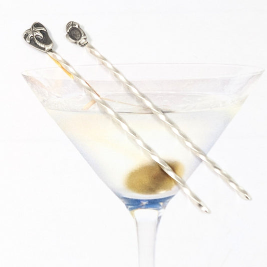 Pair of sterling silver cocktail picks. One has a palm tree, the other a parrot.