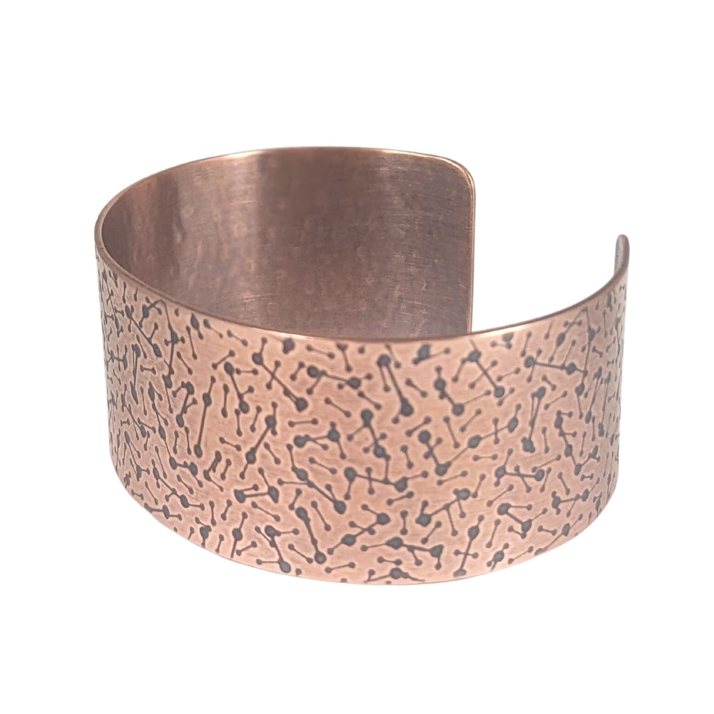 copper cuff covered in lines with dots on the ends to represent a meteor design