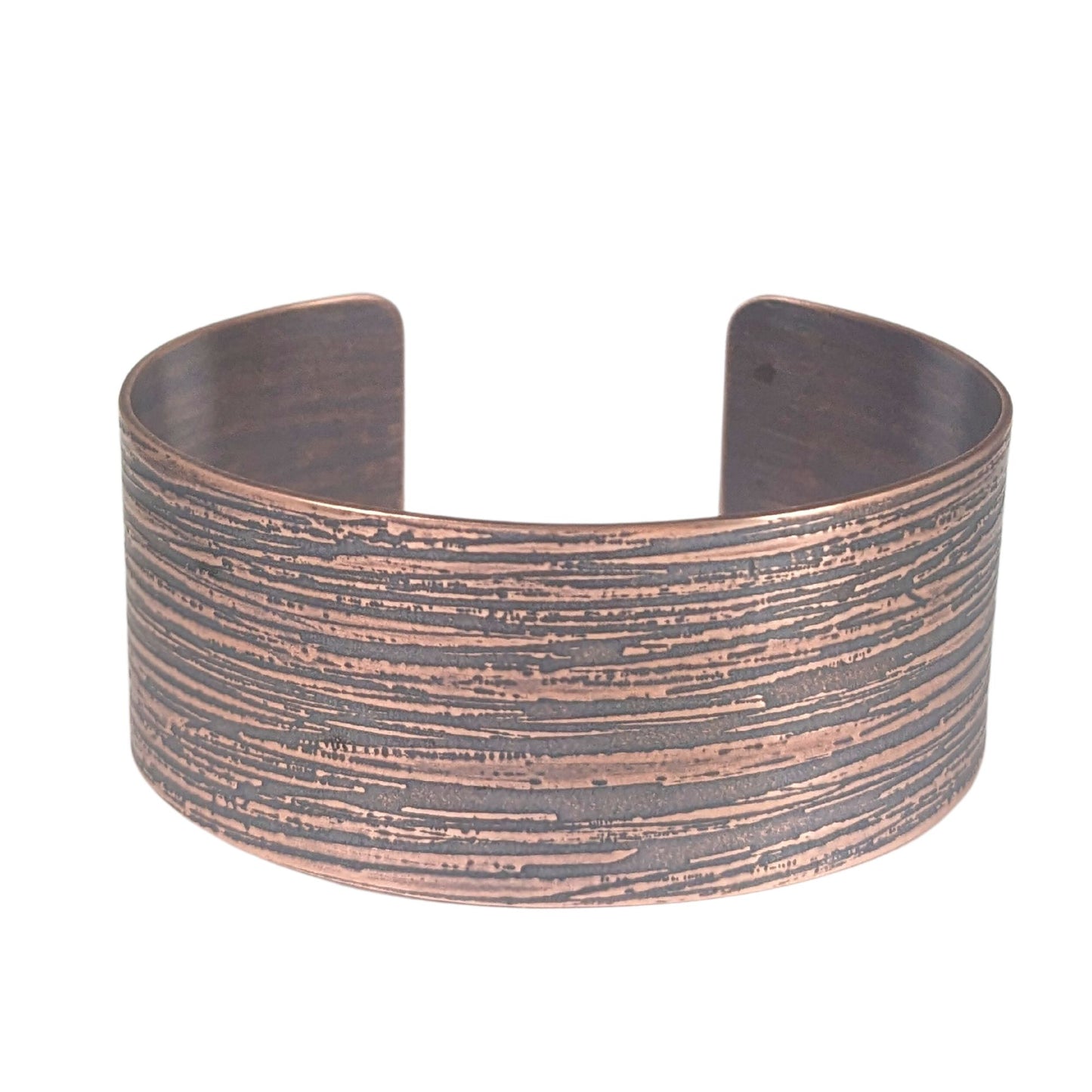 One inch wide copper cuff bracelet with an impressed texture that resembles raw silk fabric. The texture is horizontal and covers the entire cuff.