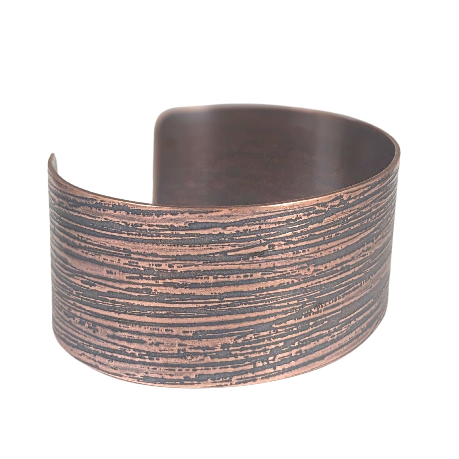 One inch wide copper cuff bracelet with an impressed texture that resembles raw silk fabric. The texture is horizontal and covers the entire cuff.