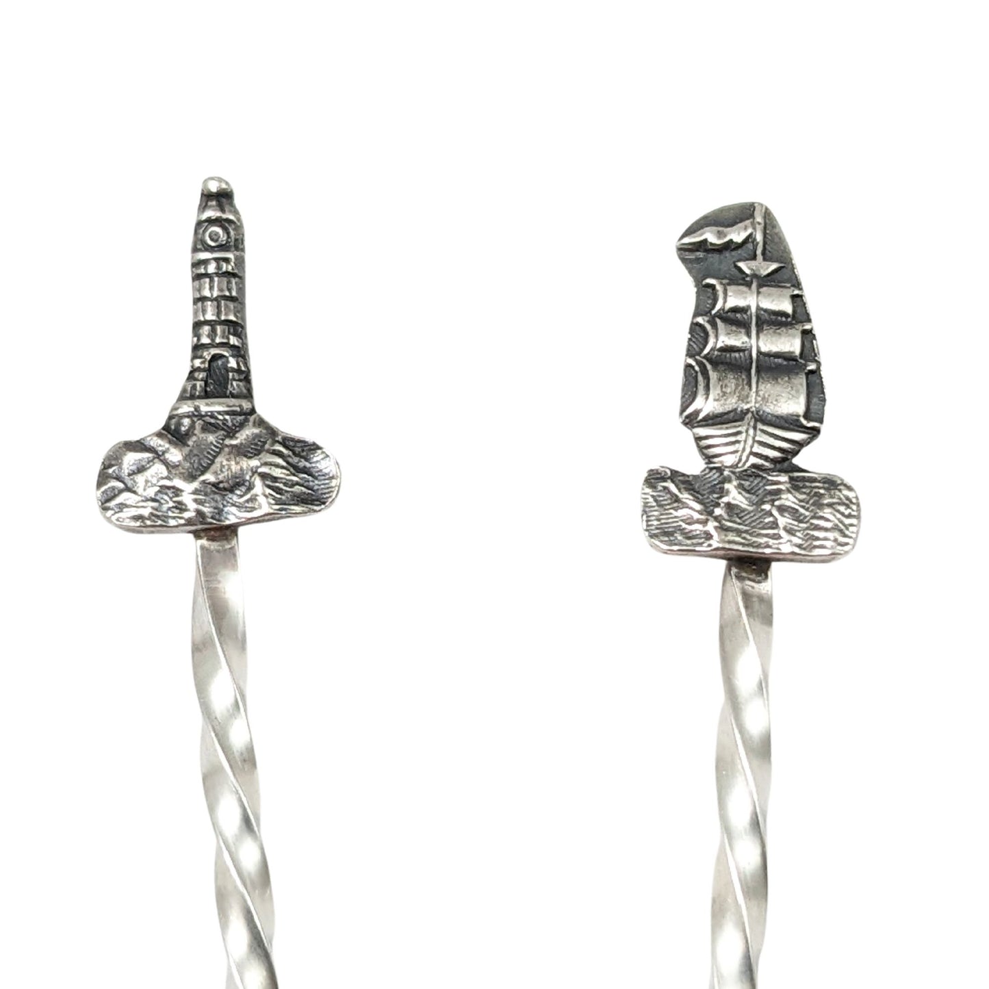 Pair of sterling silver cocktail picks. One has a lighthouse on top, the other has a tall ship.