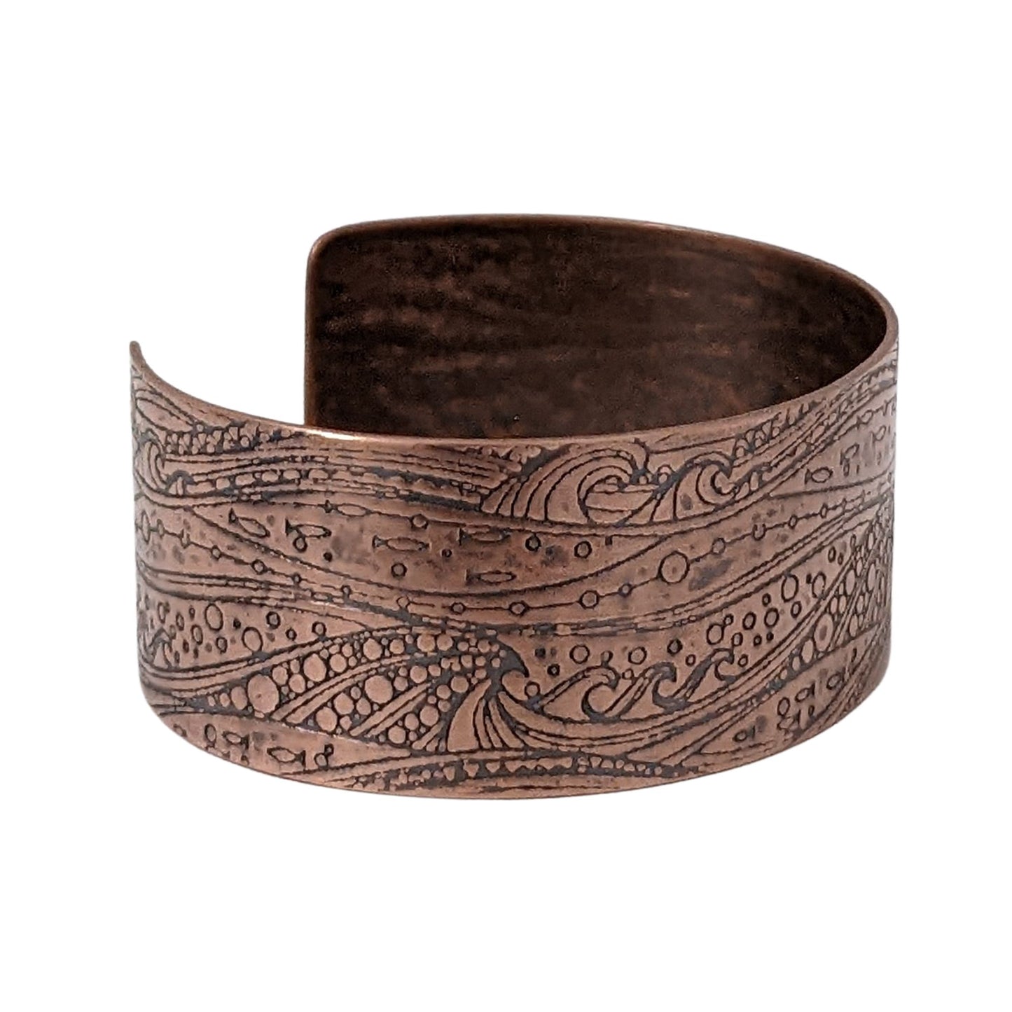 One inch wide copper cuff with a pattern of cresting waves, small fish, and air bubbles. The impression is darkened to highlight the details