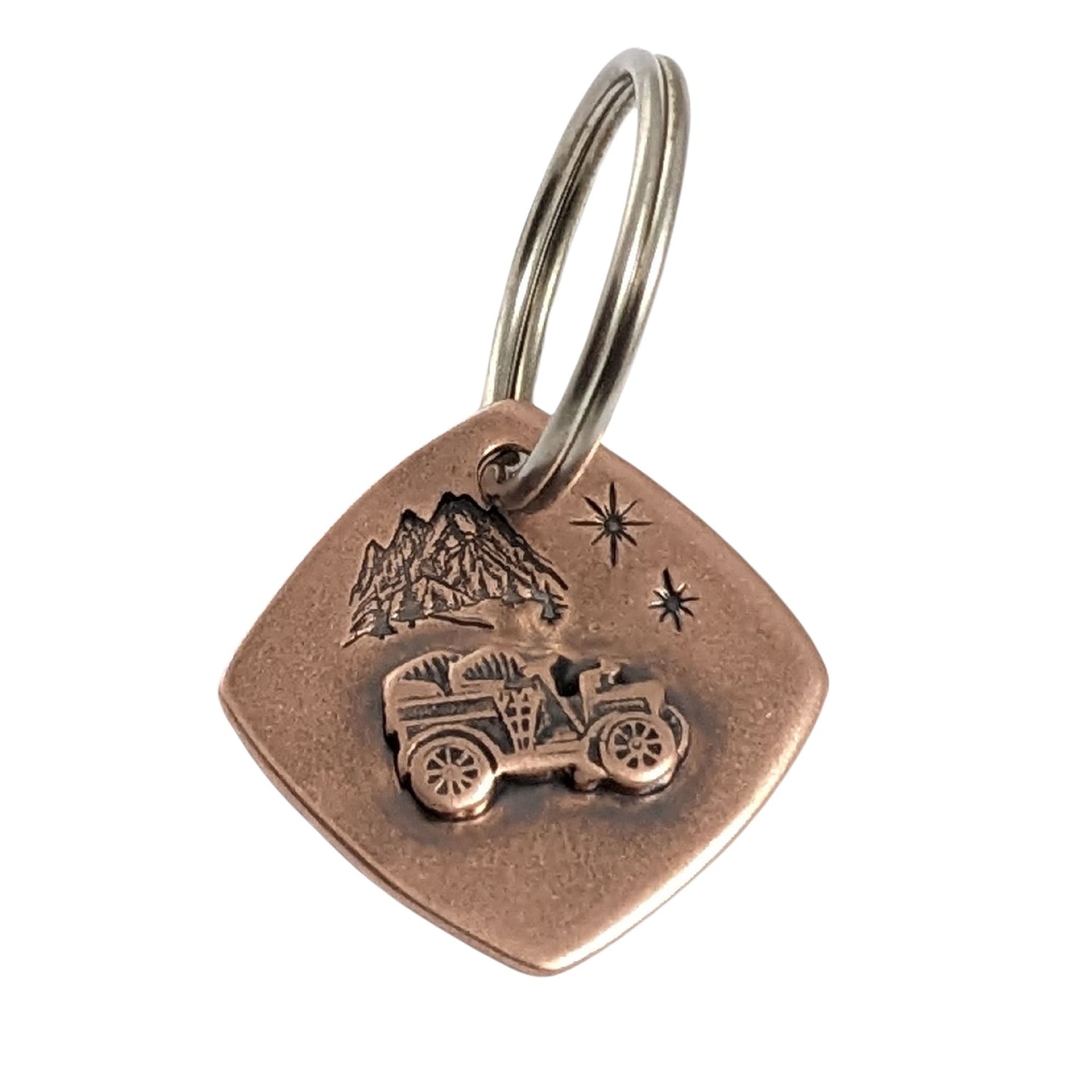 square copper keychain with raised antique car. background is mountains and sparking stars.