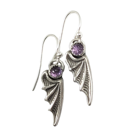Bat wing shaped earrings with a rose cut light purple amethyst gemstone on top. On silver ear wires.