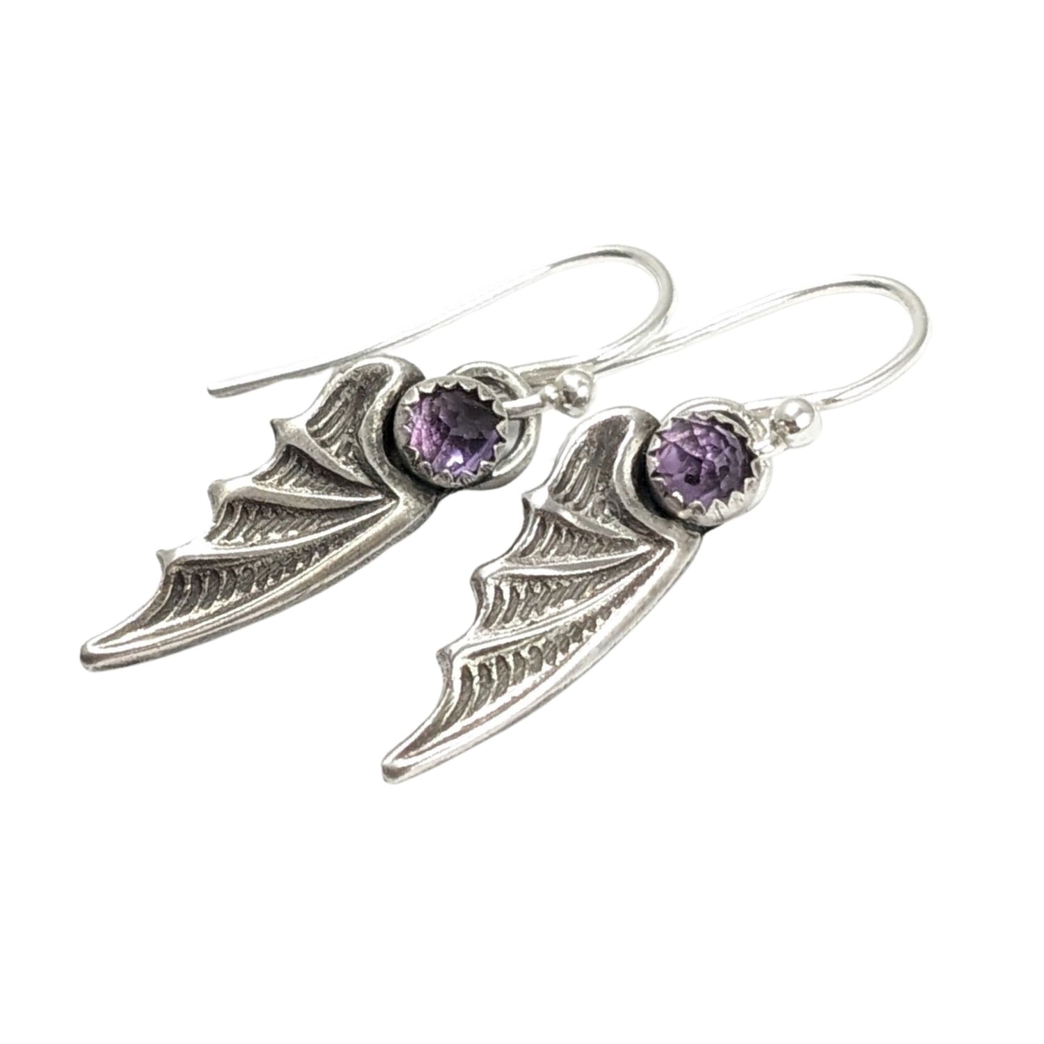 Bat wing shaped earrings with a rose cut light purple amethyst gemstone on top. On silver ear wires.