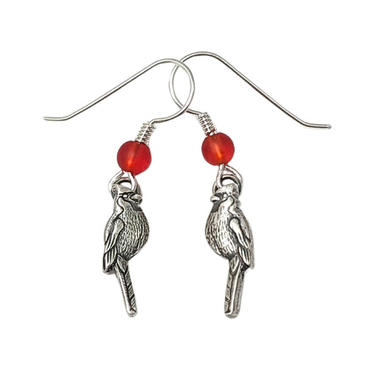 Cardinal birds as sterling silver earrings. There is one left facing Cardinal and one right facing cardinal. Above the Cardinals, attached to the ear wire, is a red Czech glass bead.
