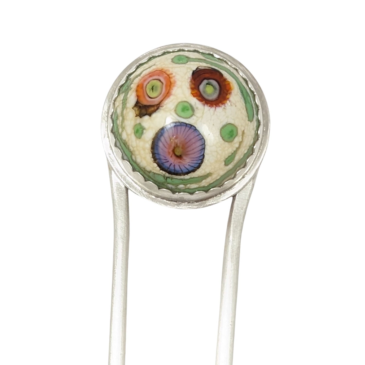 Sterling silver hair fork with a round lampwork glass stone at the top. The glass is pale yellow with ribbons of green around the edge and three abstract forms that look like flowers - one red, one orange, and one blue/pink.